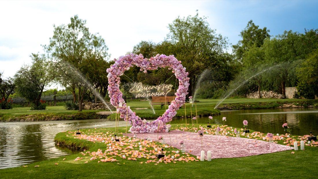 Corazón gigante de rosas con letrero ¿Quieres ser mi novia? junto al lago