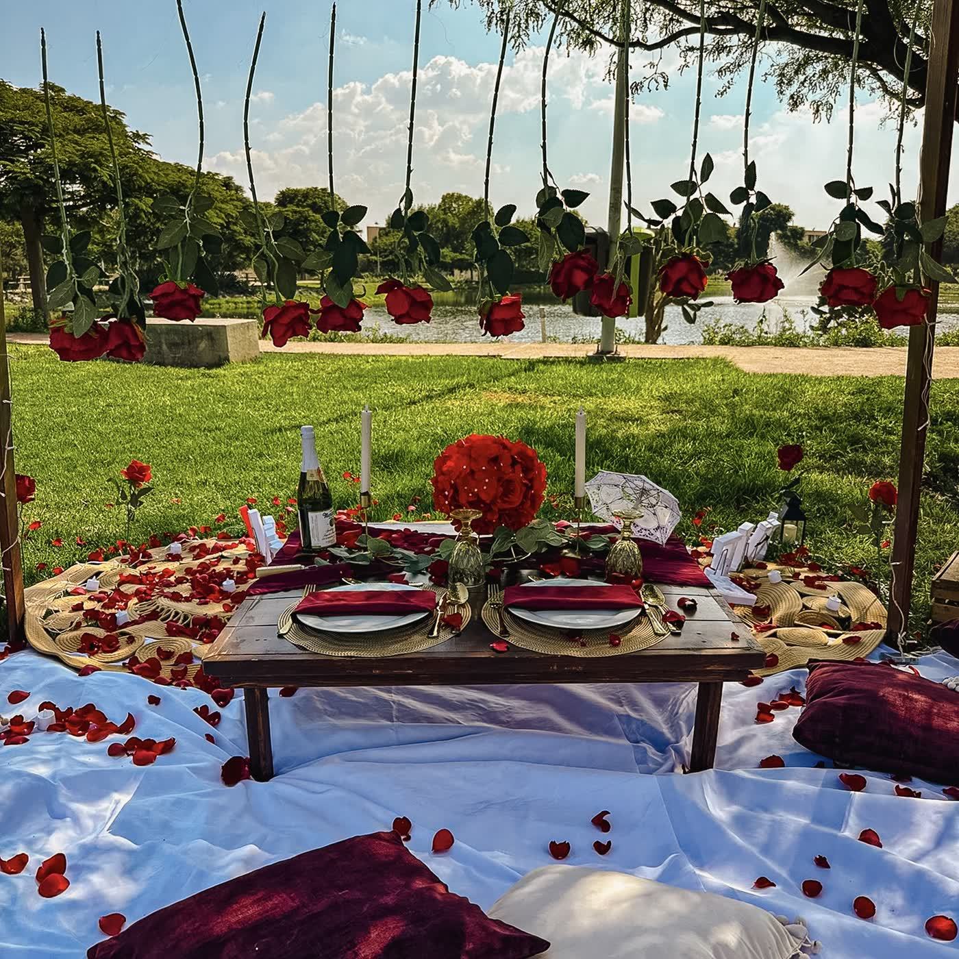 Mesa romántica junto al lago con rosas rojas colgantes