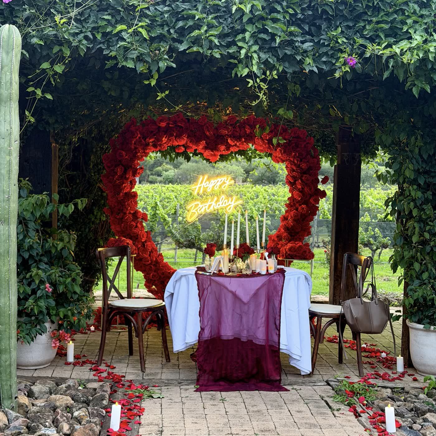 Corazón de rosas rojas con letrero Happy Birthday en cena de viñedo