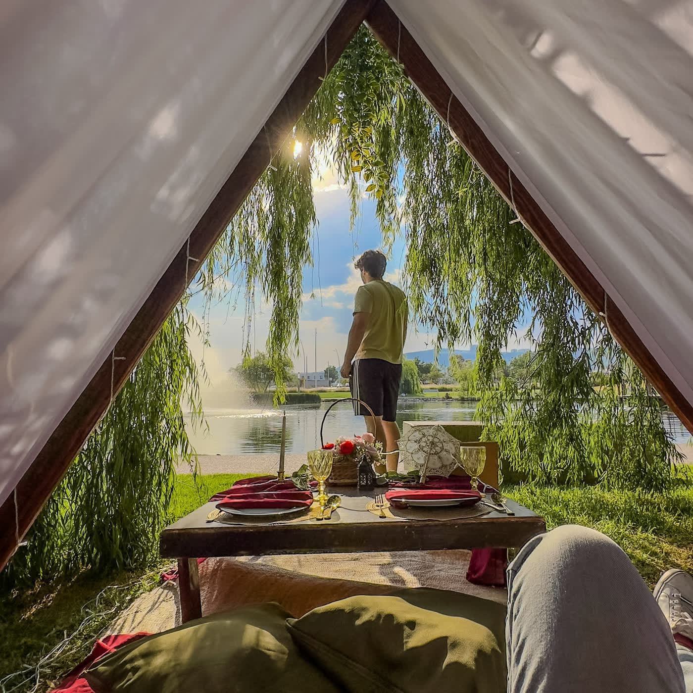 Teepee de encaje junto al lago con candelabro al atardecer para fecha especial