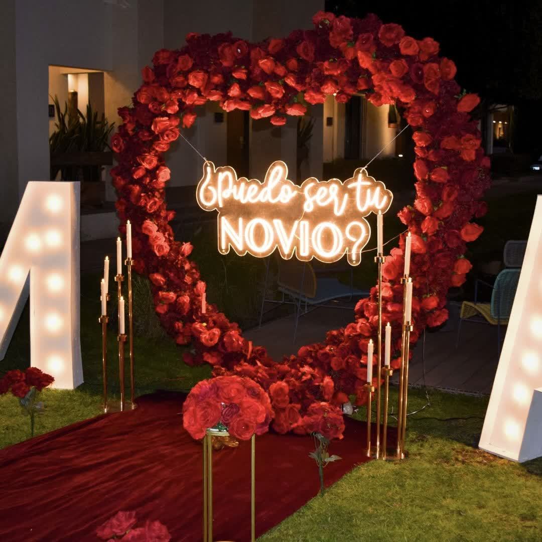 Corazón de rosas rojas con letrero neón ¿Puedo ser tu novio? y alfombra roja con velas